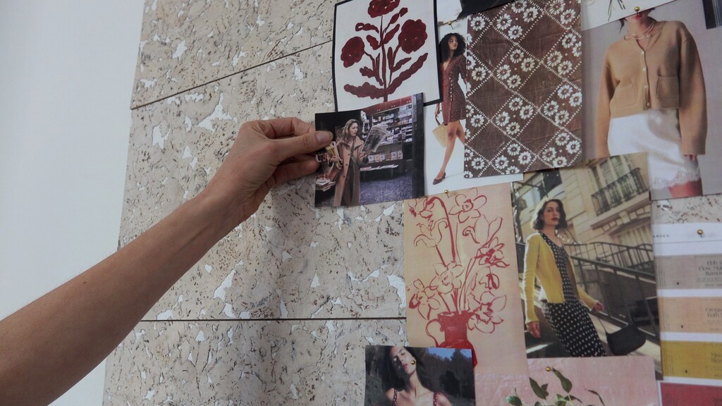 close-up of hands arranging inspiration photos and fabric swatches on a mood board
