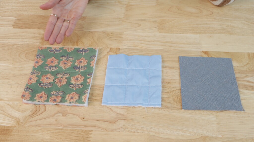 Hands holding various samples of pre-quilted fabrics in different colors and textures