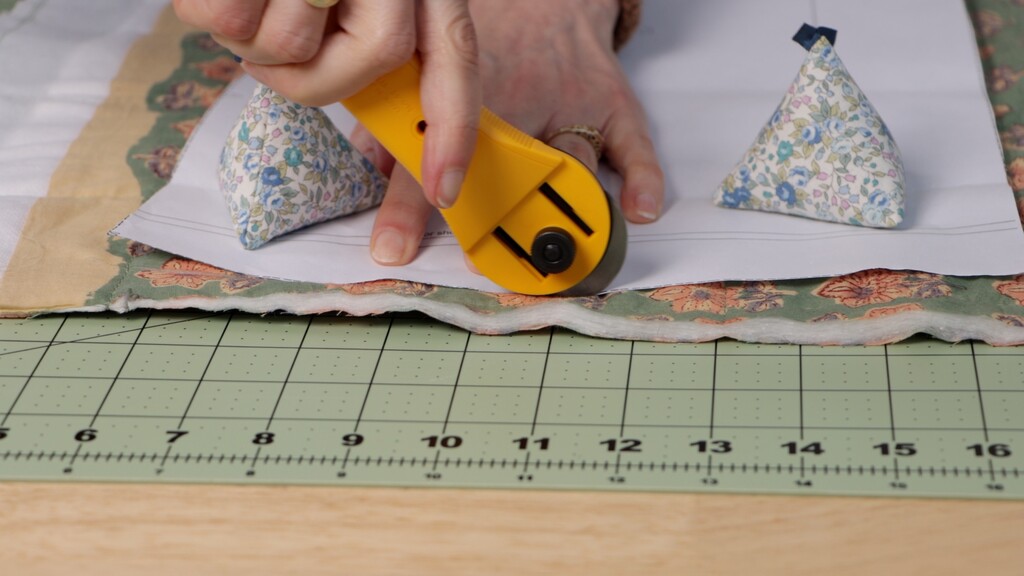 Cutting mat with pre-quilted fabric laid flat with pattern pieces and weights